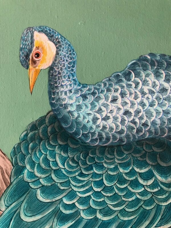 A painting of a blue peacock on a green wall.