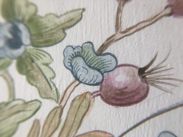 A close up of a painting of flowers and berries.