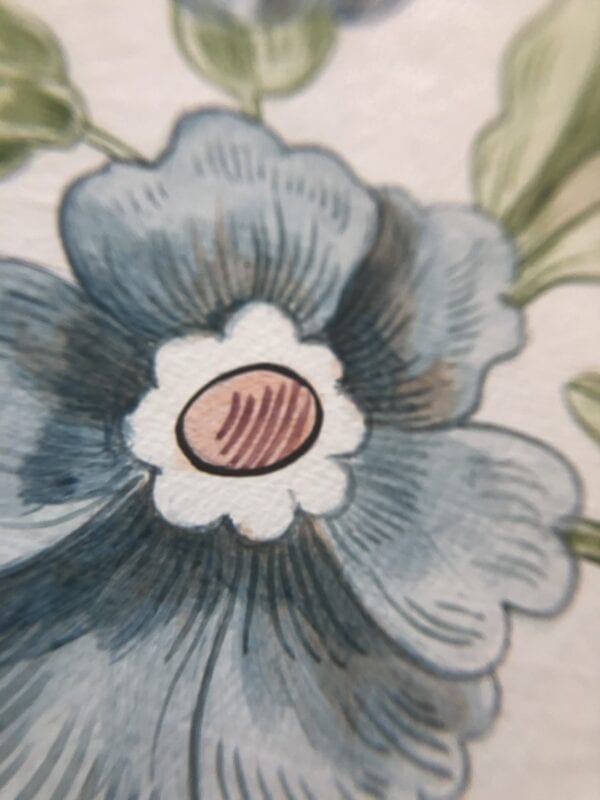 A close up of a blue flower on a piece of paper.